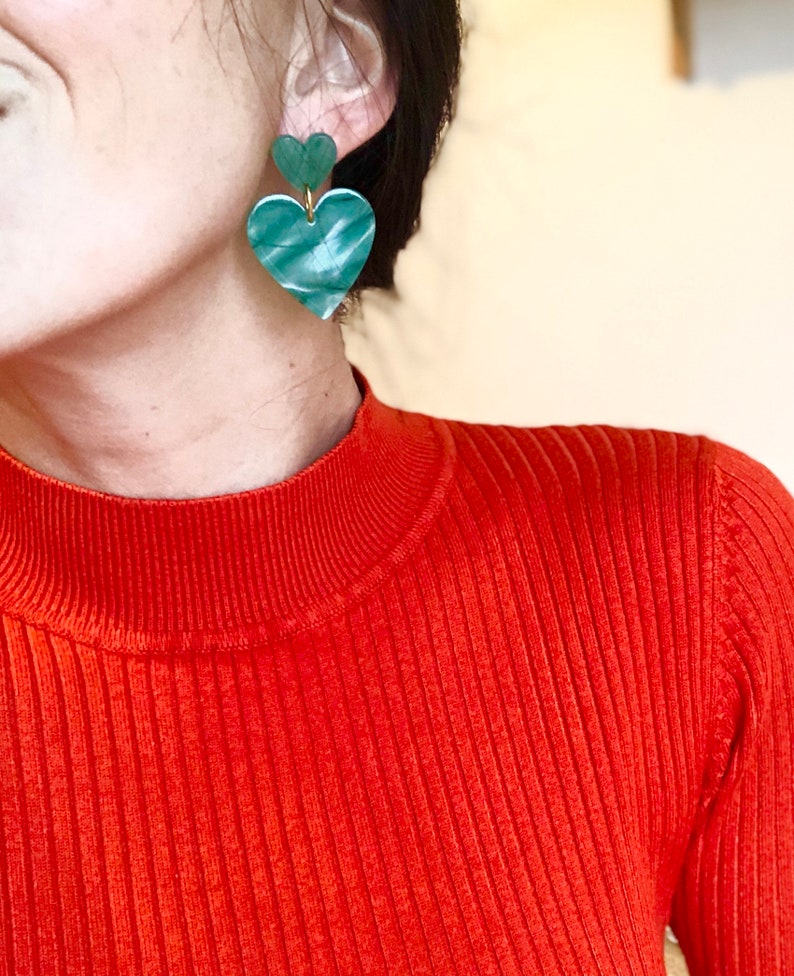 May include: A pair of green heart-shaped earrings with a marbled pattern. The earrings are made of two hearts stacked on top of each other.