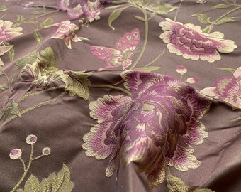 Può includere: Un tessuto marrone con un motivo floreale ricamato in tonalità rosa e oro. Il tessuto presenta grandi peonie e foglie e steli più piccoli.