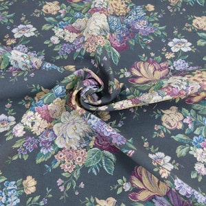 May include: A dark gray fabric with a floral pattern. The fabric is woven with a variety of flowers in shades of pink, purple, yellow, and green.
