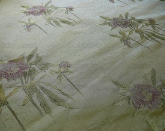 May include: A close-up of a beige fabric with a floral pattern. The flowers are pink and green and have a slightly raised texture.