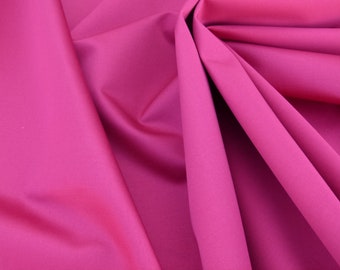 Puede incluir: Primer plano de una tela lisa de color rosa con una textura suave y fluida. La tela está doblada y drapeada, creando una sensación de movimiento y elegancia.
