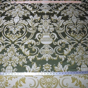 Pu&ograve; includere: Tessuto verde con un motivo damascato bianco e oro con motivi floreali e vasi decorati. Il tessuto ha una lucentezza discreta e una sensazione di lusso.