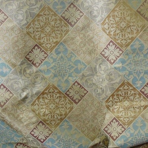 May include: A beige fabric with a repeating pattern of diamond shapes. The diamonds are filled with different floral designs in shades of blue, brown, and pink.