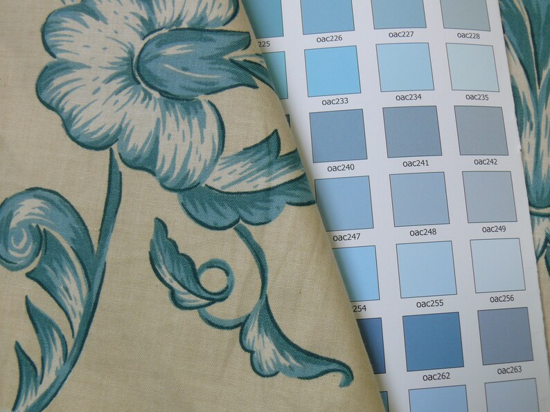 May include: A fabric swatch with a blue floral pattern is placed on top of a color chart with various shades of blue. The color chart has the color codes for each shade of blue.