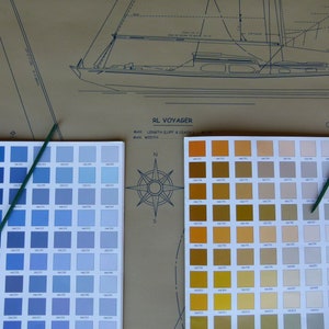 Puede incluir: Dos cartas de colores para pintura de barcos, una con tonos azules y la otra con tonos amarillos, naranjas y marrones. Las cartas est&aacute;n etiquetadas como "RL Voyager" y "Spinnaker".