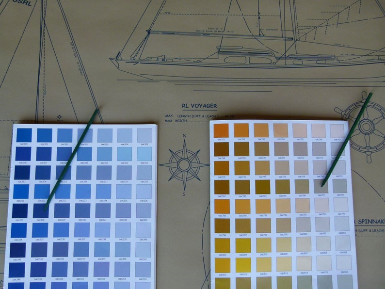Puede incluir: Dos cartas de colores para pintura de barcos, una con tonos azules y la otra con tonos amarillos, naranjas y marrones. Las cartas est&aacute;n etiquetadas como "RL Voyager" y "Spinnaker".
