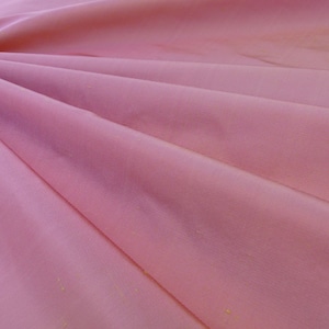 May include: A soft, pink fabric with a subtle sheen. The fabric is draped and folded, creating a smooth, flowing texture.