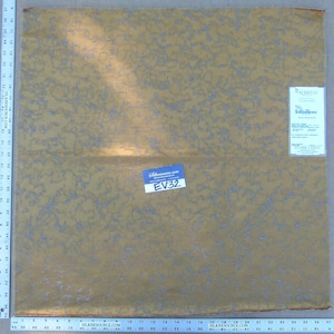 Peut inclure: Gros plan sur un tissu doré avec un motif argenté. Le tissu a un léger brillant et une surface texturée. Le tissu est étiqueté avec le code "EV32".