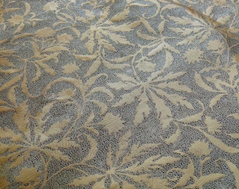 Puede incluir: Primer plano de una tela texturizada con un patrón floral. La tela es de color beige claro con un diseño floral beige más oscuro.