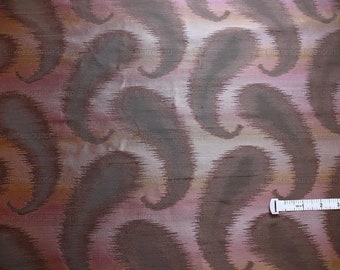 May include: Close-up of a fabric with a paisley pattern in shades of brown, pink, and orange. A white measuring tape is partially visible at the bottom of the image.