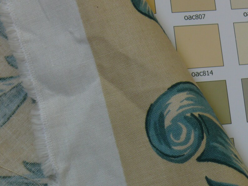 May include: Close-up of a beige fabric with a blue and white swirl pattern. The fabric is next to a color chart with the codes "oac807" and "oac814".