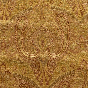 May include: A gold fabric with a paisley pattern in shades of red and brown.