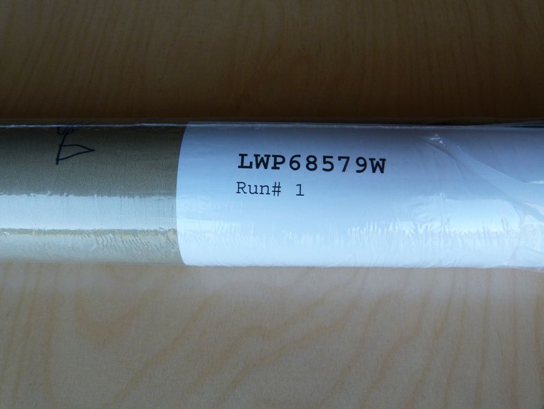 Puede incluir: Primer plano de una etiqueta blanca con el texto "LWP68579W" y "Run # 1" impreso en ella. La etiqueta est&aacute; unida a un objeto enrollado marr&oacute;n y blanco.