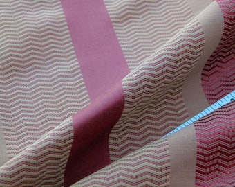 Puede incluir: Primer plano de una tela con un patrón de chevron en beige y rosa. La tela tiene un diseño a rayas con rayas alternas anchas y estrechas.