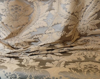 May include: A close-up of a beige and brown fabric with a damask pattern. The fabric is folded and has a soft, luxurious feel.