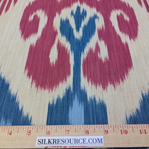 May include: Close-up of a fabric with a blue, white, and red ikat pattern. The fabric is measured with a ruler that reads "SILKRESOURCE.COM".