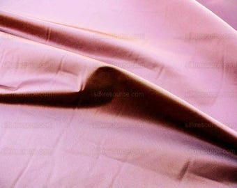 May include: Close-up of a smooth, silky fabric in a deep rose color. The fabric is draped and folded, creating soft, flowing lines.