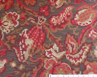 May include: Close-up of a brown fabric with a red and gold floral pattern. The fabric has a textured surface and a repeating pattern of flowers and leaves.