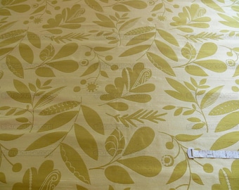 May include: A close-up of a fabric with a repeating pattern of stylized leaves and flowers in a muted yellow color on a cream background.