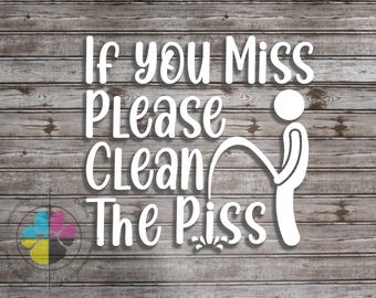 May include: White vinyl decal with the text "If you Miss Please Clean The Piss" and a stick figure urinating. The decal is on a wooden background. A logo is in the lower left corner.