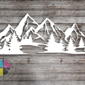 May include: White mountain and forest silhouette decal. The design features detailed mountain peaks and evergreen trees, suitable for wall decor. The decal is displayed against a wooden background.