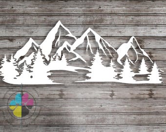 May include: White mountain and forest silhouette decal. The design features detailed mountain peaks and evergreen trees, suitable for wall decor. The decal is displayed against a wooden background.