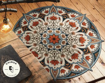 May include: A round, colorful mandala rug with intricate patterns in shades of blue, orange, and brown. The rug has a floral design with a central flower in shades of blue and orange.