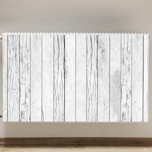 Puede incluir: Radiador blanco con un patrón de veta de madera. El radiador tiene una perilla plateada y dos tuberías plateadas.