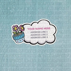 May include: A white cloud-shaped sticker with a black outline. The sticker has the text "YOUR NAME HERE" and "ADDRESS LINE 1", "ADDRESS LINE 2", and "ADDRESS LINE 3" printed on it. A small blue pot with a happy face and two pink flowers with yellow centers is to the left of the cloud.