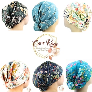 May include: Assortment of floral patterned scrub caps in various colors, including dark green, teal, and cream. The caps feature different floral designs and are displayed on mannequin heads. The Care Kaps logo is also visible.