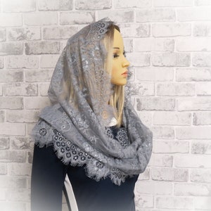 May include: A gray lace shawl with a delicate floral pattern. The shawl is draped over a mannequin's head and shoulders.