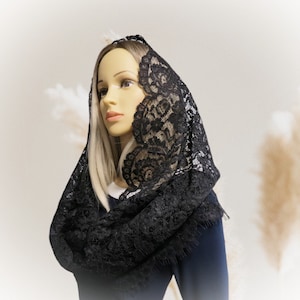 May include: A black lace mantilla with a scalloped edge. The mantilla is draped over a mannequin's head and shoulders.