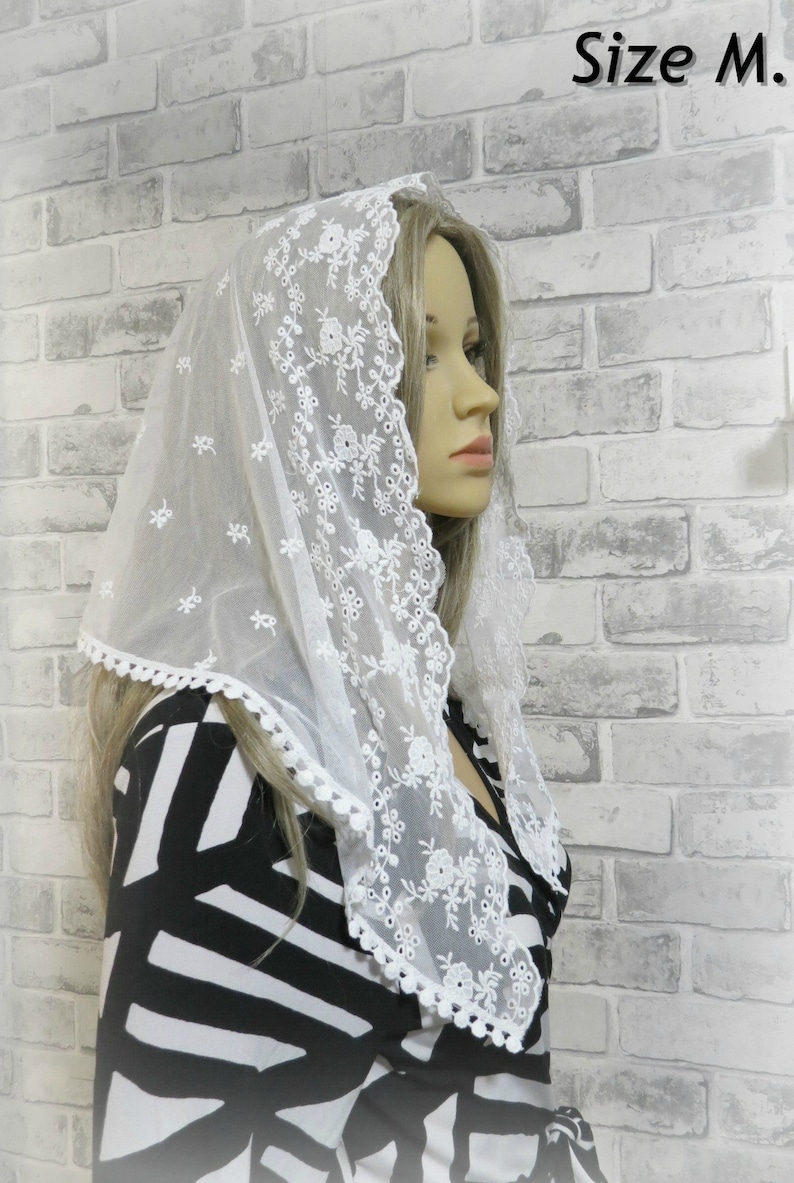 Peut inclure: Voile en dentelle blanche avec broderie florale et bord festonn&eacute;. Le voile est port&eacute; par une personne aux cheveux blonds. Le texte "Taille M." est visible dans le coin sup&eacute;rieur droit de l'image.