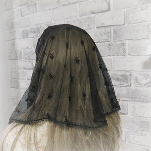 Peut inclure: Voile en dentelle noire avec un motif floral. Le voile a un bord festonn&eacute; et est fait d'un tissu transparent.