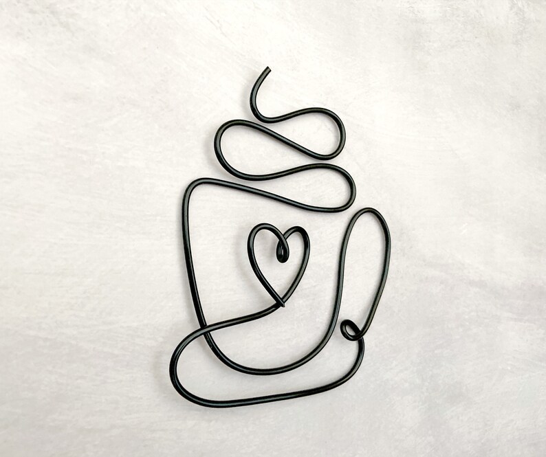 Puede incluir: Escultura de alambre negro de una taza de caf&eacute; con un coraz&oacute;n en su interior. La escultura est&aacute; hecha de una sola pieza de alambre y est&aacute; dise&ntilde;ada para parecer una taza de caf&eacute; con vapor que sale de la parte superior.