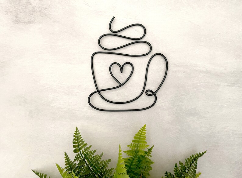 Puede incluir: Escultura de alambre negro de una taza de caf&eacute; con un coraz&oacute;n en el centro. La taza tiene un dise&ntilde;o de espiral en la parte superior, que representa crema batida.