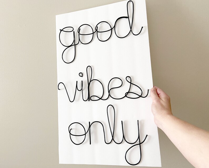 May include: A white background with black wire lettering that reads "good vibes only".