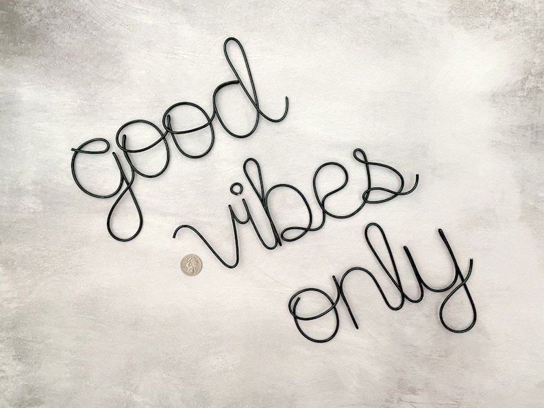 May include: Black wire wall decor with the words "good vibes only" in a cursive font.