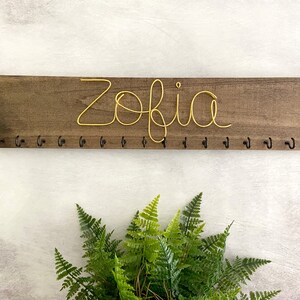May include: A weathered wooden sign displaying the words "Welcome to our porch" in white. The sign has a distressed appearance, ideal for adding a touch of rustic charm to a porch or garden.