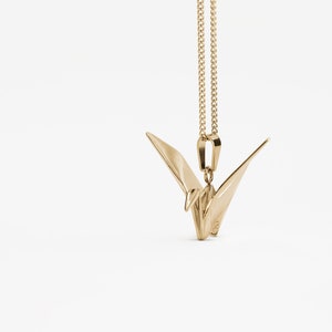 Peut inclure: Un collier avec un pendentif en forme de grue origami en or. La grue est un symbole de paix et de bonne chance.