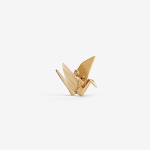 Peut inclure: Un pendentif en forme de grue en origami dor&eacute;. La grue est un symbole japonais traditionnel de paix et de bonne chance.