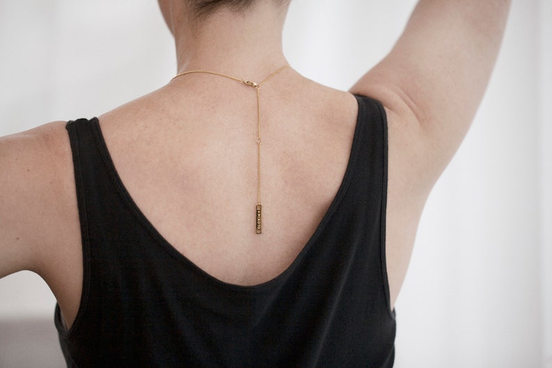 Peut inclure: Un collier en cha&icirc;ne dor&eacute;e avec un petit pendentif rectangulaire suspendu &agrave; l'arri&egrave;re du cou.