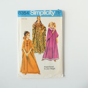Puede incluir: Un sobre de patrón de costura Simplicity 8354 con ilustraciones de tres túnicas largas estilo caftán. Los diseños incluyen una túnica naranja sólida, una túnica con estampado de diamantes y una túnica magenta sólida con borde blanco.