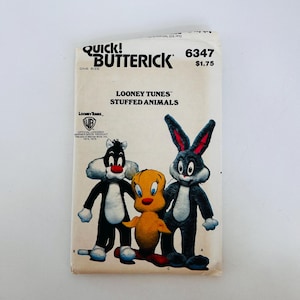 Puede incluir: Un patrón de costura Butterick vintage para peluches de Looney Tunes. El patrón presenta ilustraciones de Silvestre el Gato, Piolín y Bugs Bunny. El patrón está etiquetado como "Quick! Butterick" e incluye el logotipo de Warner Bros.