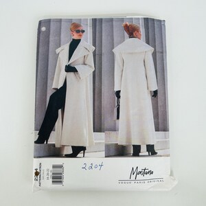 May include: A sewing pattern envelope for a long, off-white coat with a wide collar, shown from front and back views. The text on the envelope includes 2204, 18-20-22, Montana, and Vogue Paris Original. The coat is worn over black clothing.