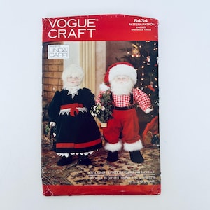 May include: Vogue Craft pattern 8434 showing Santa Claus and Mrs. Claus dolls. The cover displays the dolls in red and black outfits with white trim. The text "ONE SIZE" is visible on the pattern.