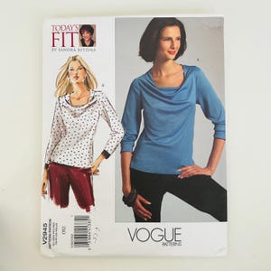 May include: A Vogue Patterns sewing pattern envelope for Today's Fit by Sandra Betzina, style V2945. The cover displays a long-sleeve top with a cowl neckline, shown as a white garment with black polka dots and a solid blue version, both with cuffs.