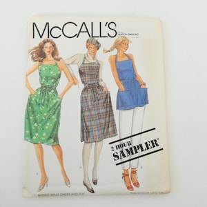 Könnte beinhalten: Ein Vintage-Schnittmuster von McCall's mit drei Damenbekleidungsdesigns. Das Schnittmuster trägt den Titel "2 Hour Sampler*" und beinhaltet ein Wickelkleid, eine karierte Schürze und eine blaue Jeans-Schürze. Der Text "Misses Wrap Dress and Top" ist am unteren Rand des Schnittmusters aufgedruckt.