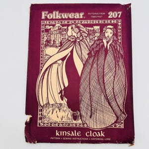 Può includere: Una busta di cartamodello Folkwear vintage, numero 207, con un'illustrazione di figure con mantelli. La busta è di un colore bordeaux intenso con illustrazioni e testo color crema. Il testo recita "kinsale cloak" e "patterns from times past."