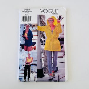 May include: Vogue Patterns 7092 sewing pattern envelope for sizes L-XL. The front features illustrations of a hooded yellow jacket with a drawstring waist, a dark blue jacket with matching shorts, and a yellow tank top with black pants on a boat.